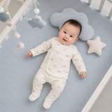 baby boy wears white oneise on bed