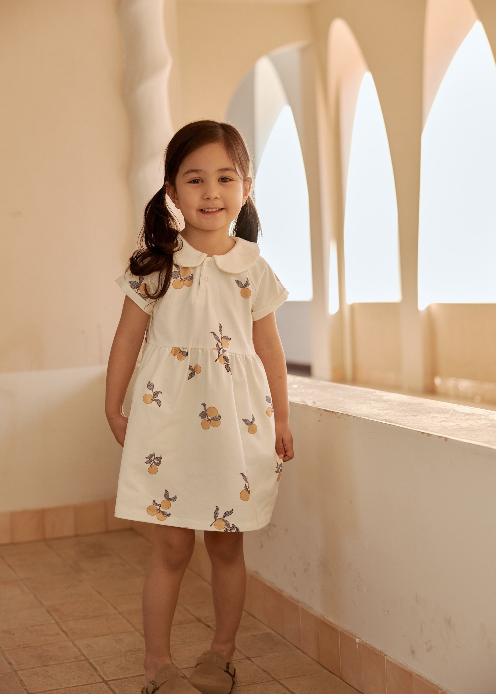 baby girl wearing organic collar dress and standing on the floor