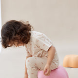 Child sitting on a pink cushion on a plain background