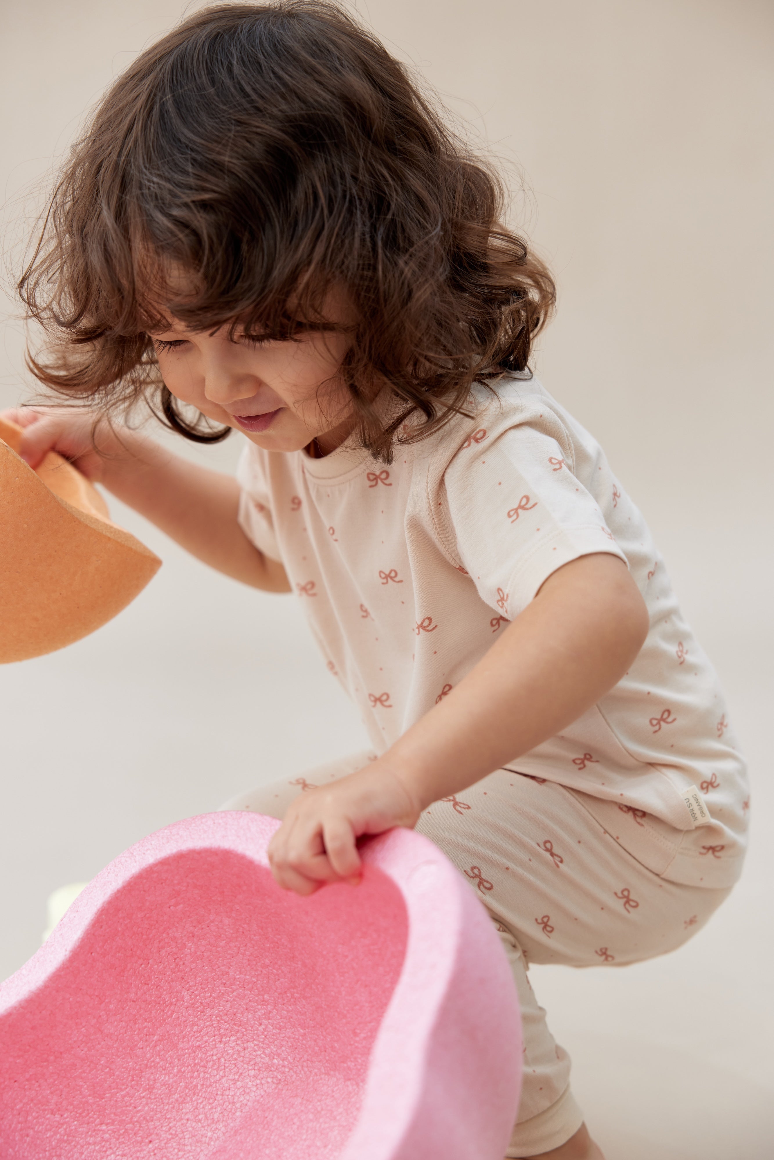 Child playing with a pink toy on a light background