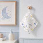 A personalized white quilted cloth pouch with a blue and yellow space print hangs from a wooden peg on a light blue wall in a nursery setting. The pouch is personalized with the name 'LUNARIS' and features a small wooden moon picture on the left.