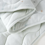 Folded light space partten quilt with subtle patterns on a white background