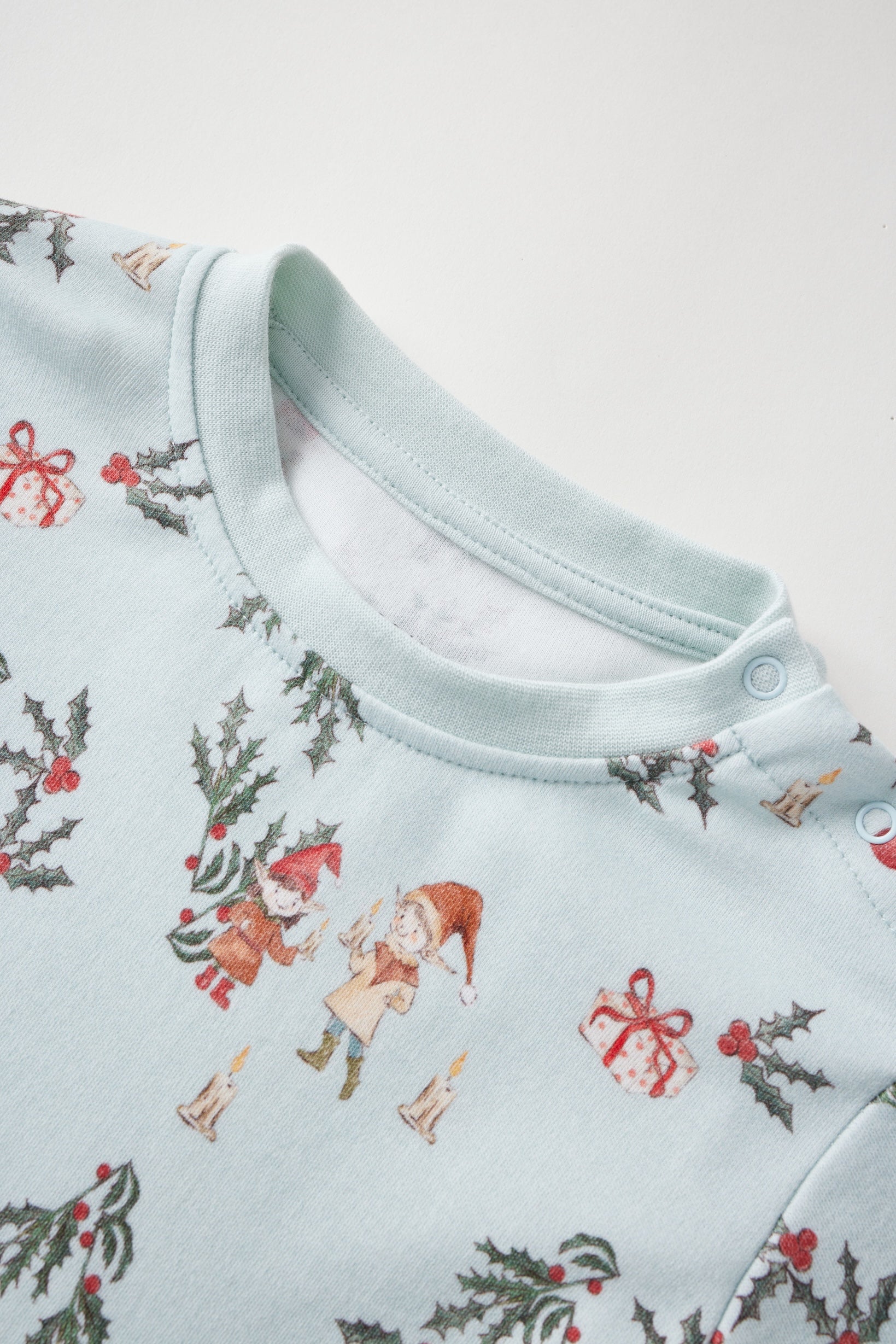 Baby pajama with Christmas-themed print on a light blue background