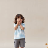 Child wearing a striped shirt and gray shorts on a plain background