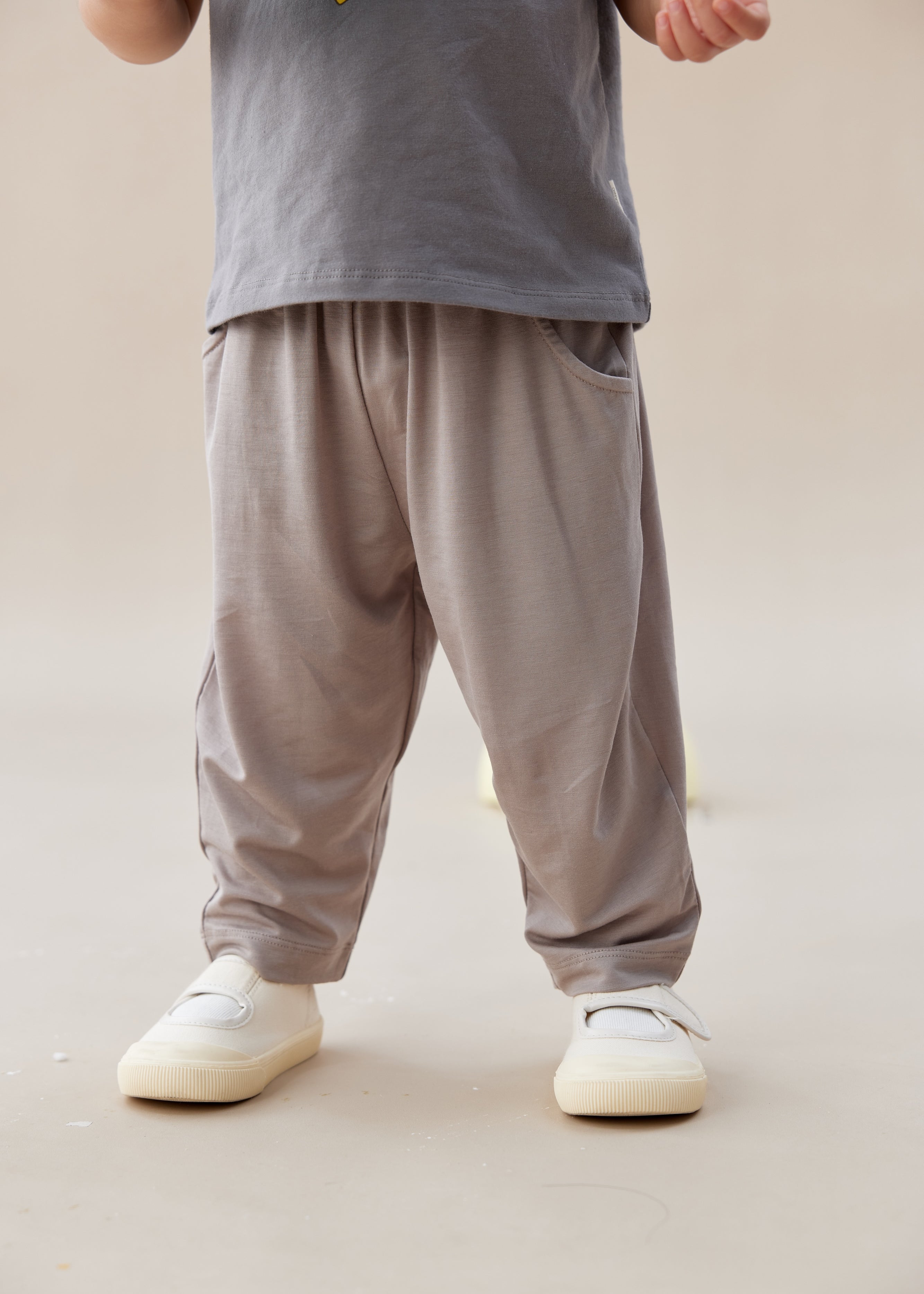 Person wearing gray pants and white shoes on a plain background