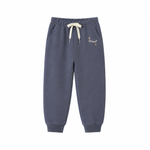 A pair of dark slate blue jogger sweatpants with a cream-colored drawstring and small gold embroidered text on the left thigh, displayed against a solid white background.