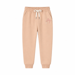 A pair of light peach-beige jogger sweatpants with an elastic waistband, white drawstring, and a small pink bow graphic on the left thigh, shown against a plain white background.