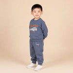 Child wearing a blue sweatshirt and pants set with text on a beige background