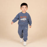 Child wearing a blue sweatshirt and pants with a 'Speed Time' graphic on a beige background