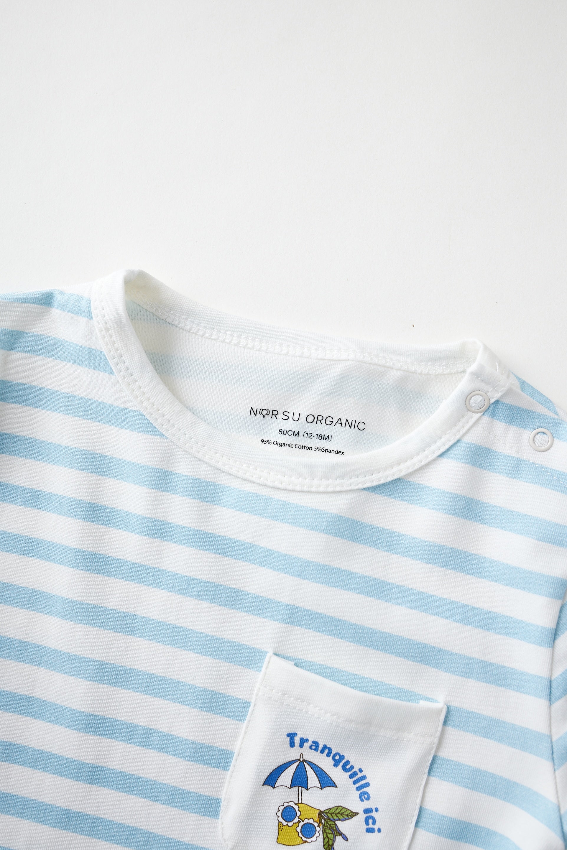 Close-up of a blue and white striped shirt with a brand label and pocket design.