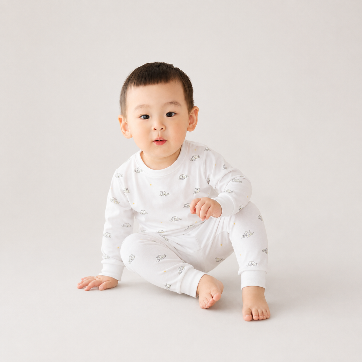 Baby wearing a white outfit with small patterns on a light gray background