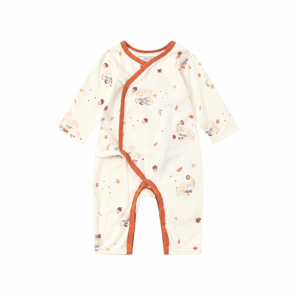 A baby long-sleeve sleep sack or romper in cream with a scattered acorn print and orange trim, shown flat on a white background.