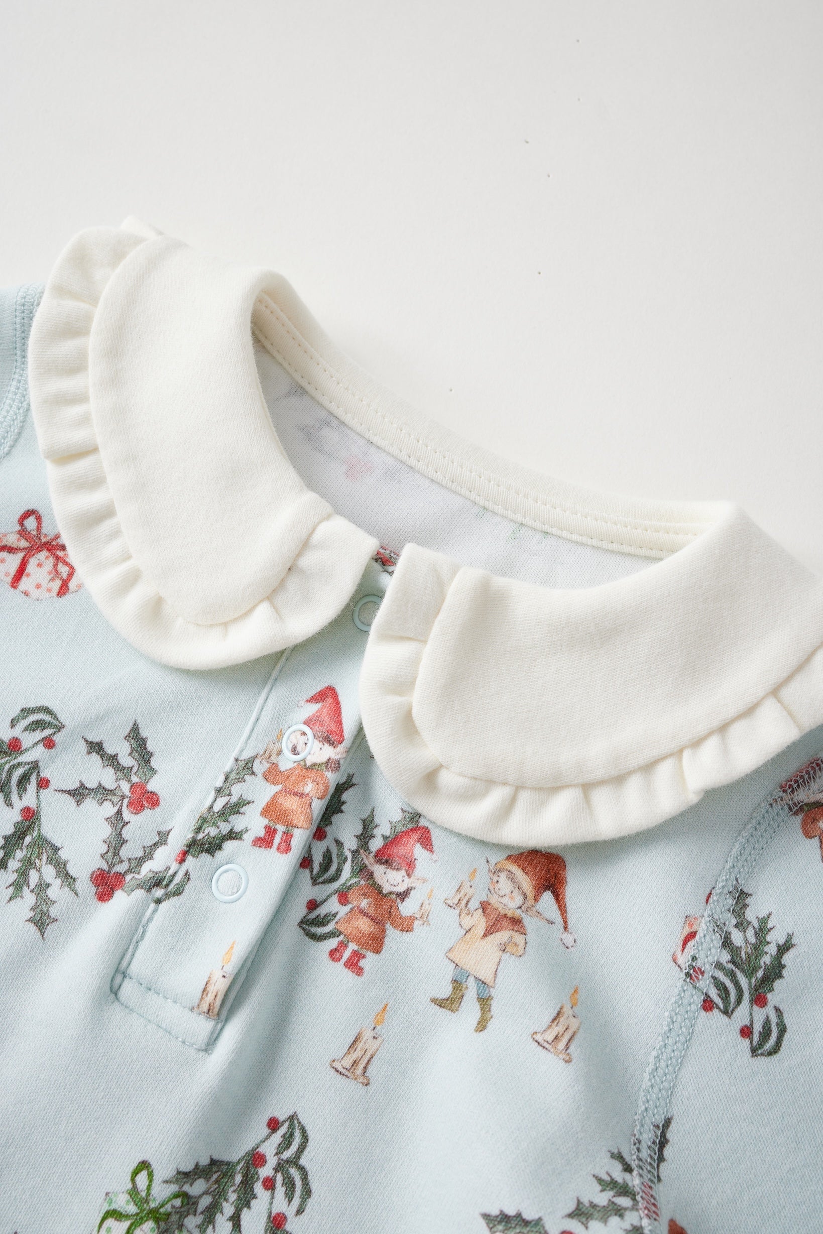 White ruffled collar on a light blue shirt with Christmas-themed design