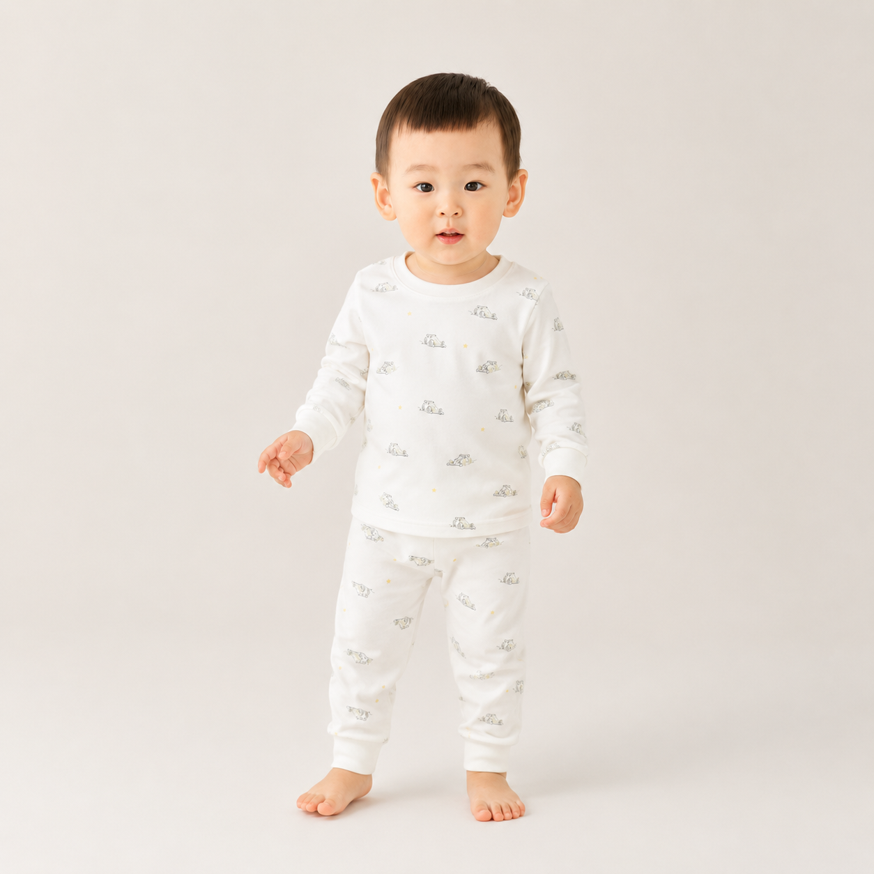 Child wearing a white pajama set with small prints on a plain background