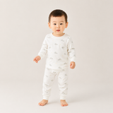 Child wearing a white pajama set with small prints on a plain background