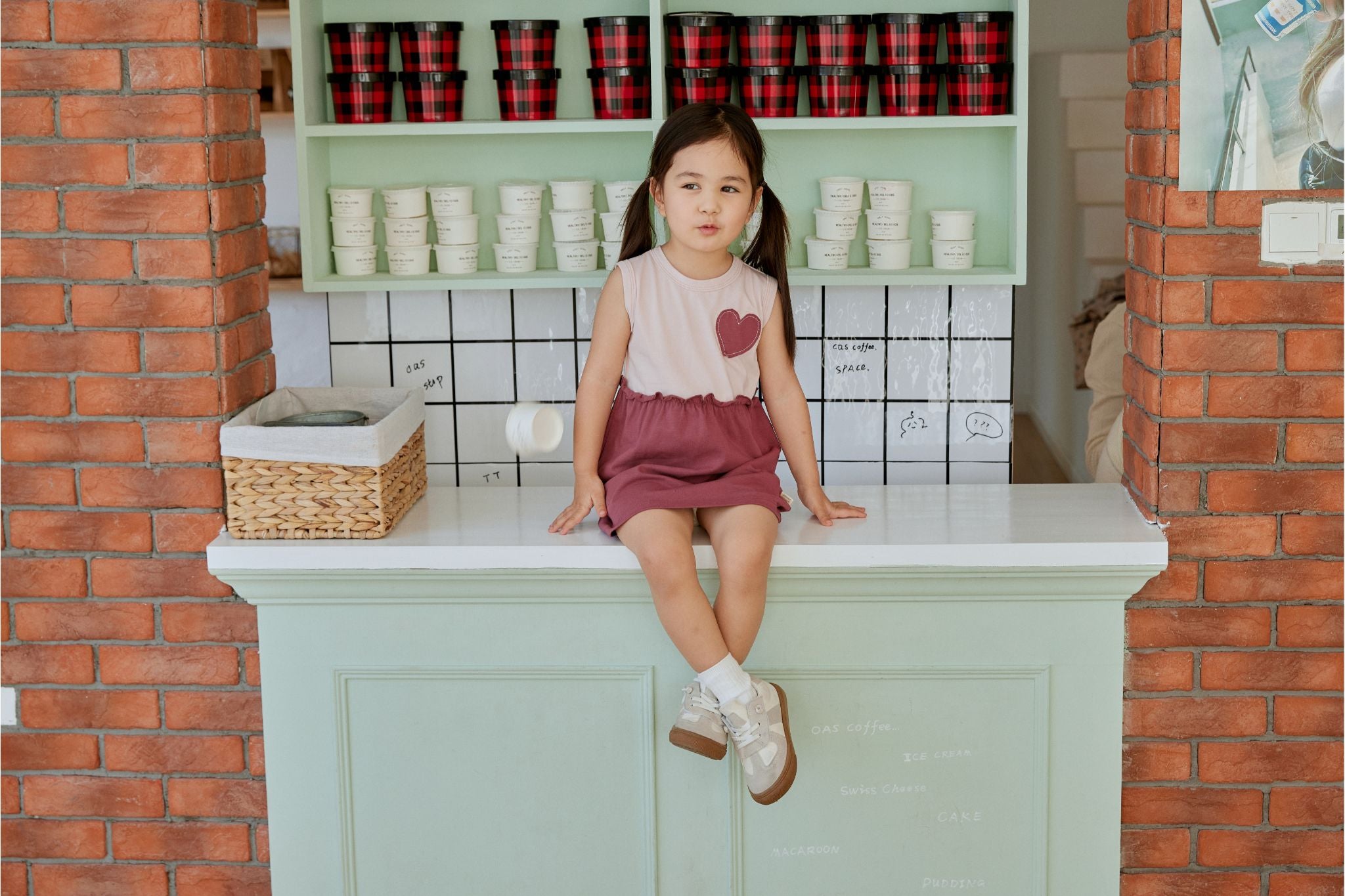 Baby girl sitting on the table and wearing a heart dress