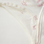 Close-up of a cream-colored fabric garment with a delicate pink bow pattern and a visible zipper.