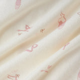 A close-up of a soft cream-colored fabric with a delicate, repeating pink ballet dancer pattern.