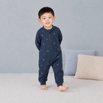 Child wearing a navy blue bodysuit with a pattern on a gray background