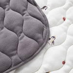 Gray quilted pad on a white surface with penguin patterns