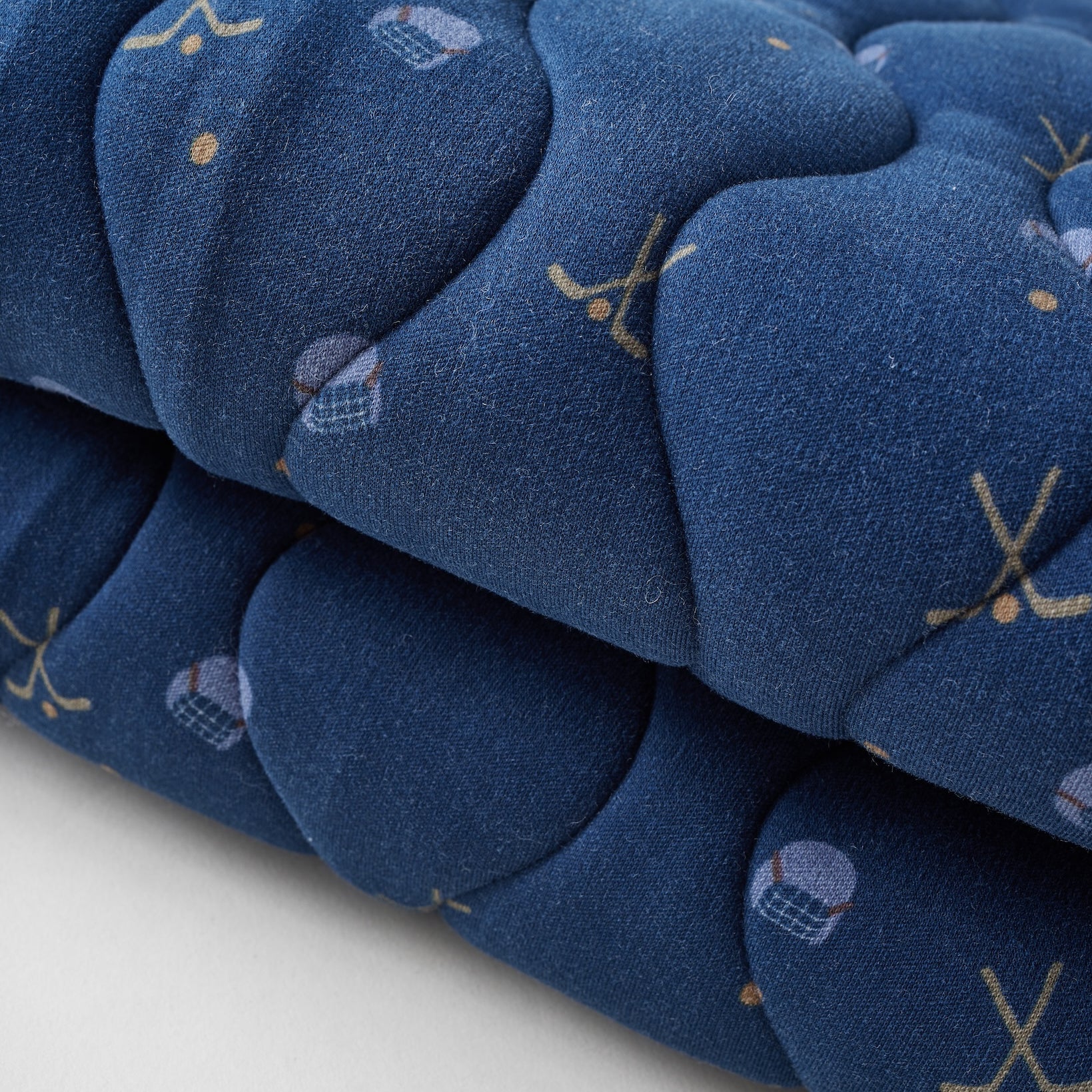 Stack of blue quilted items with patterns on a white background