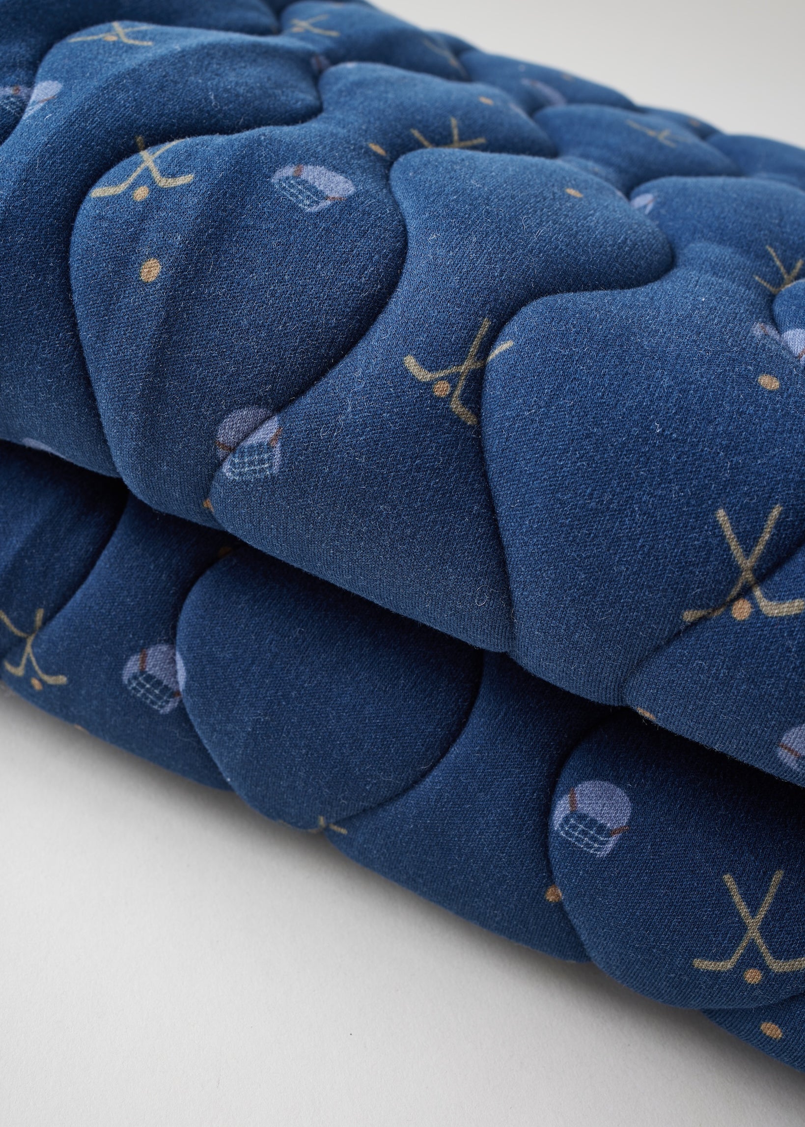 Stack of blue quilted items with patterns on a white background