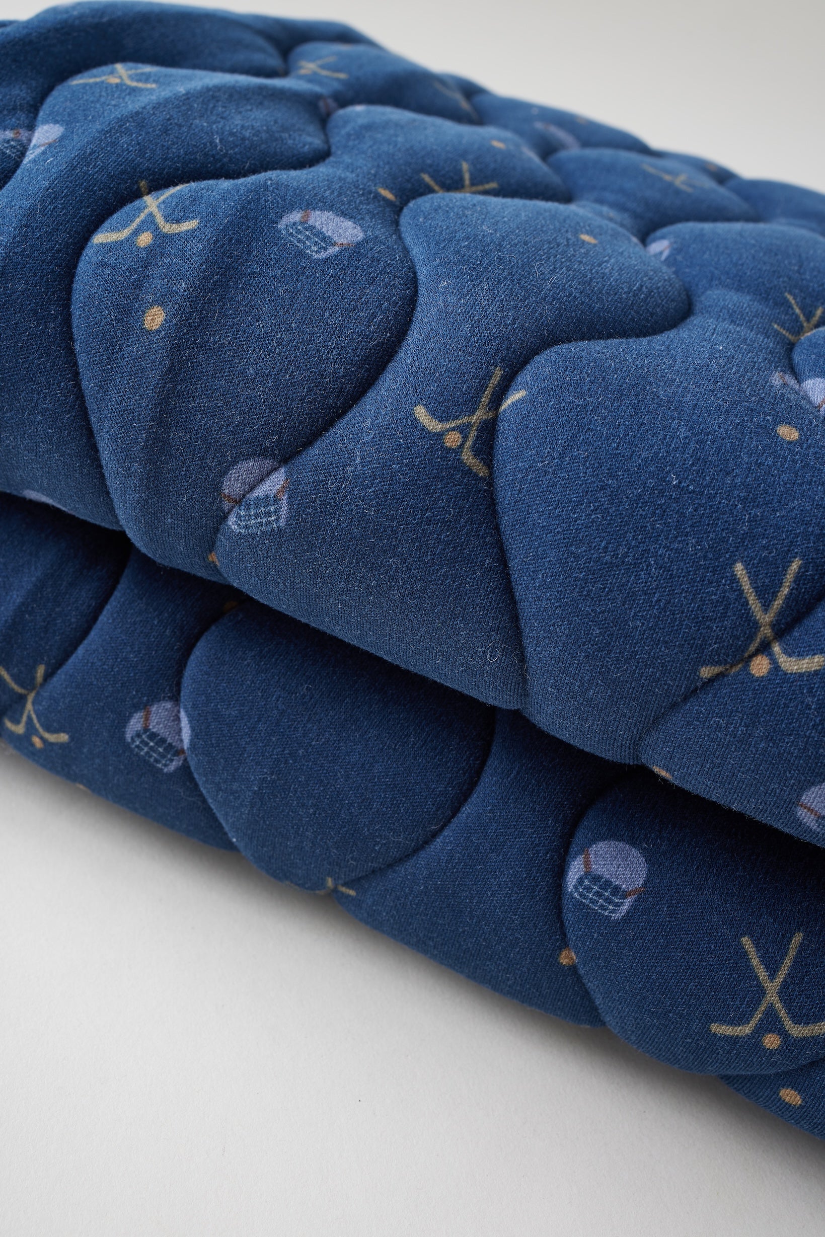 Stack of blue quilted items with patterns on a white background