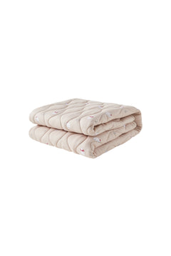 Folded beige quilt on a white background