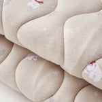 Close-up of a beige quilt with floral patterns on a white background