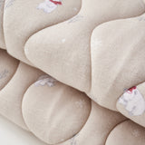 Close-up of a beige quilt with floral patterns on a white background