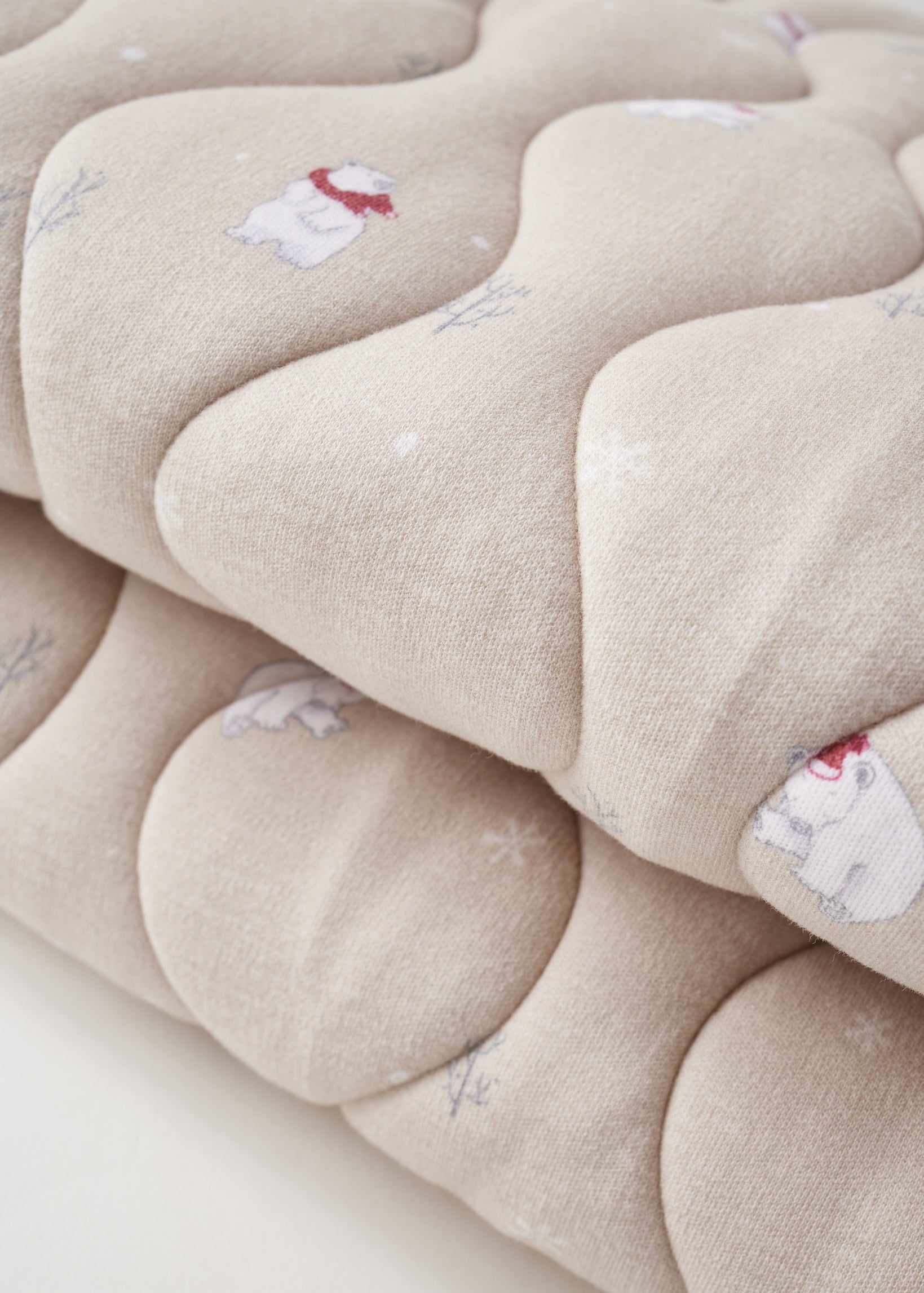 Close-up of a beige quilt with floral patterns on a white background