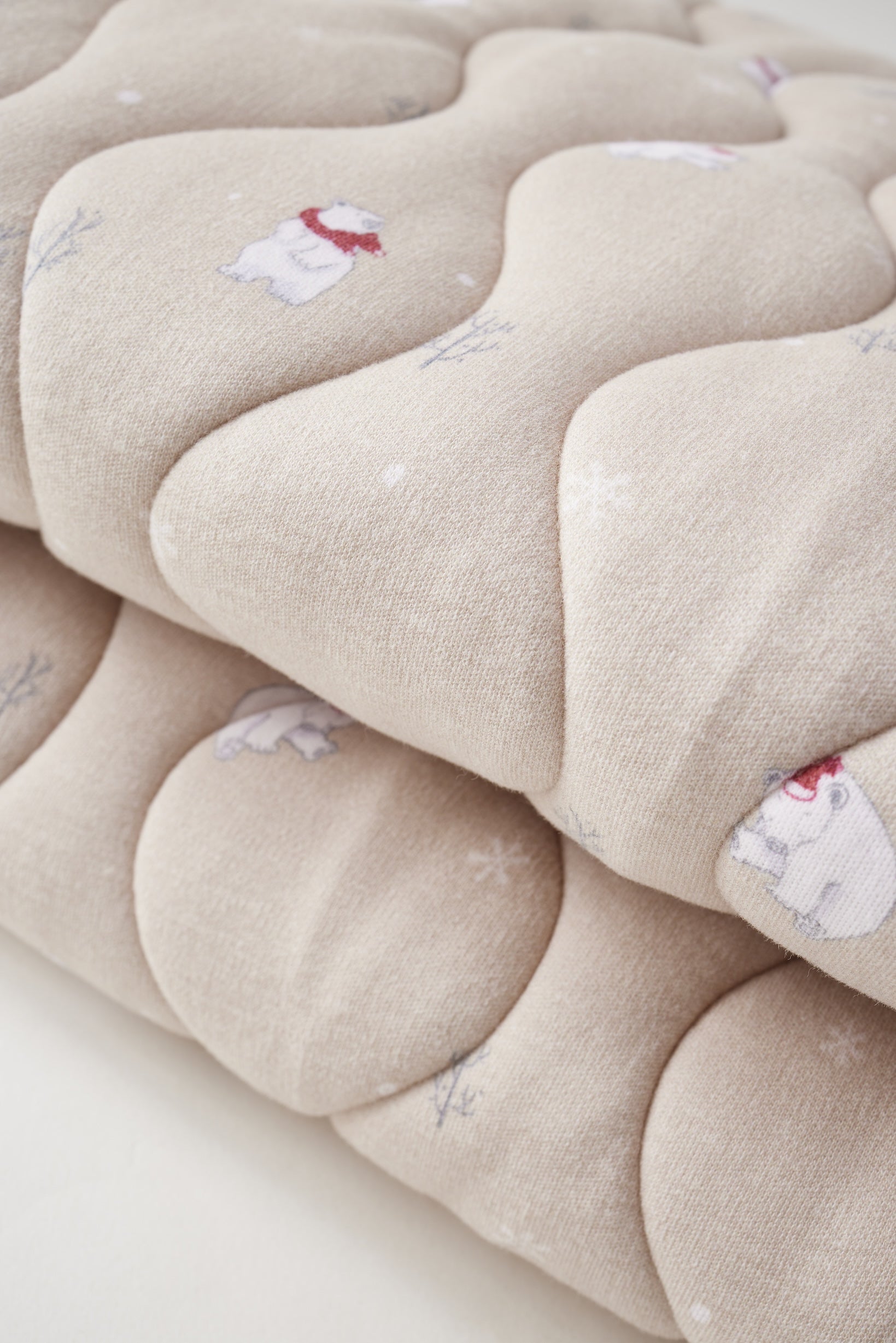 Close-up of a beige quilt with floral patterns on a white background
