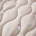 Close-up of a textured fabric surface with embroidered designs of bears and trees.