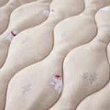 Close-up of a textured fabric surface with embroidered designs of bears and trees.