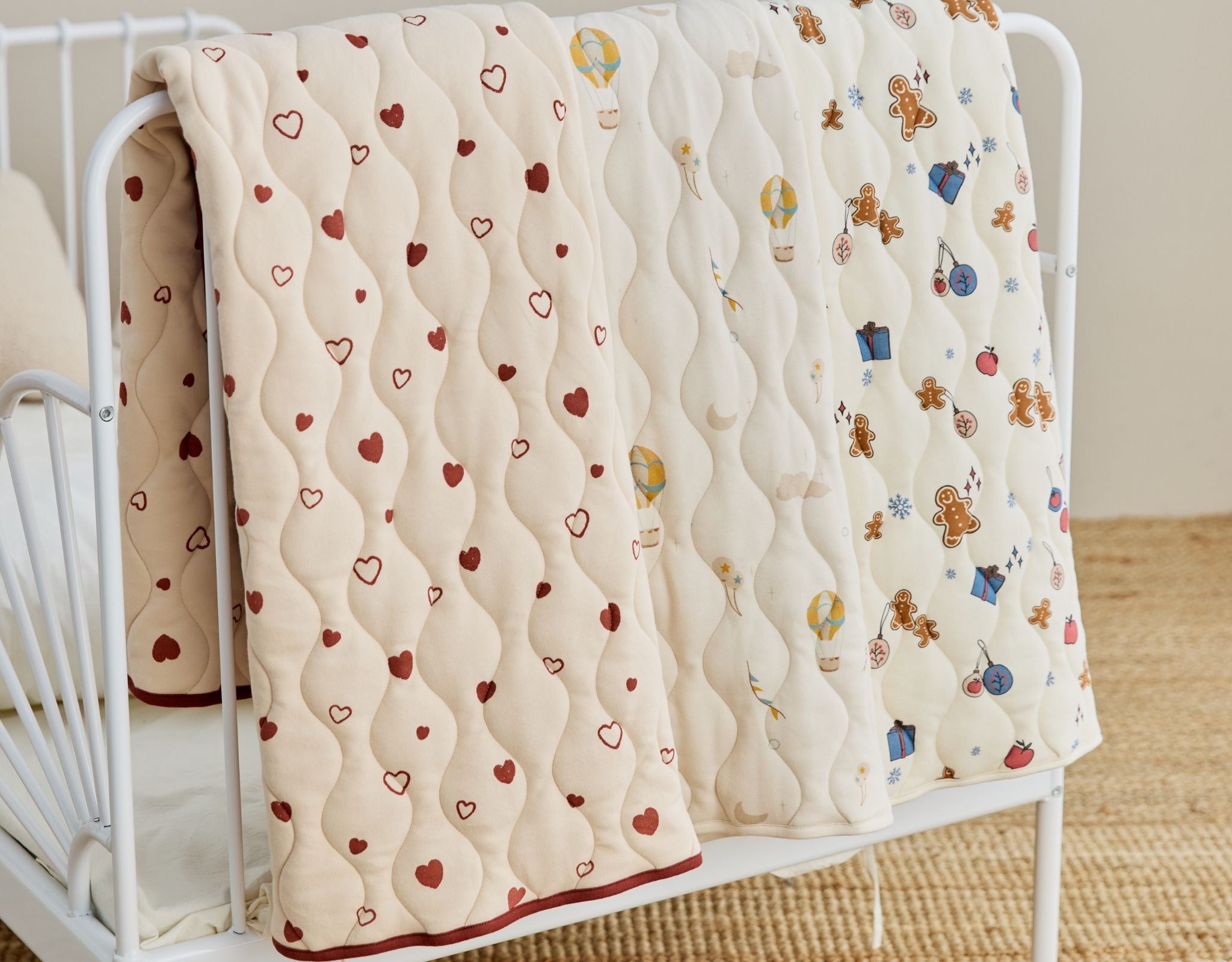 Baby crib with a quilt featuring heart patterns and cartoon characters.
