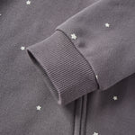 Close-up of a dark gray sweatshirt with star patterns on a plain background