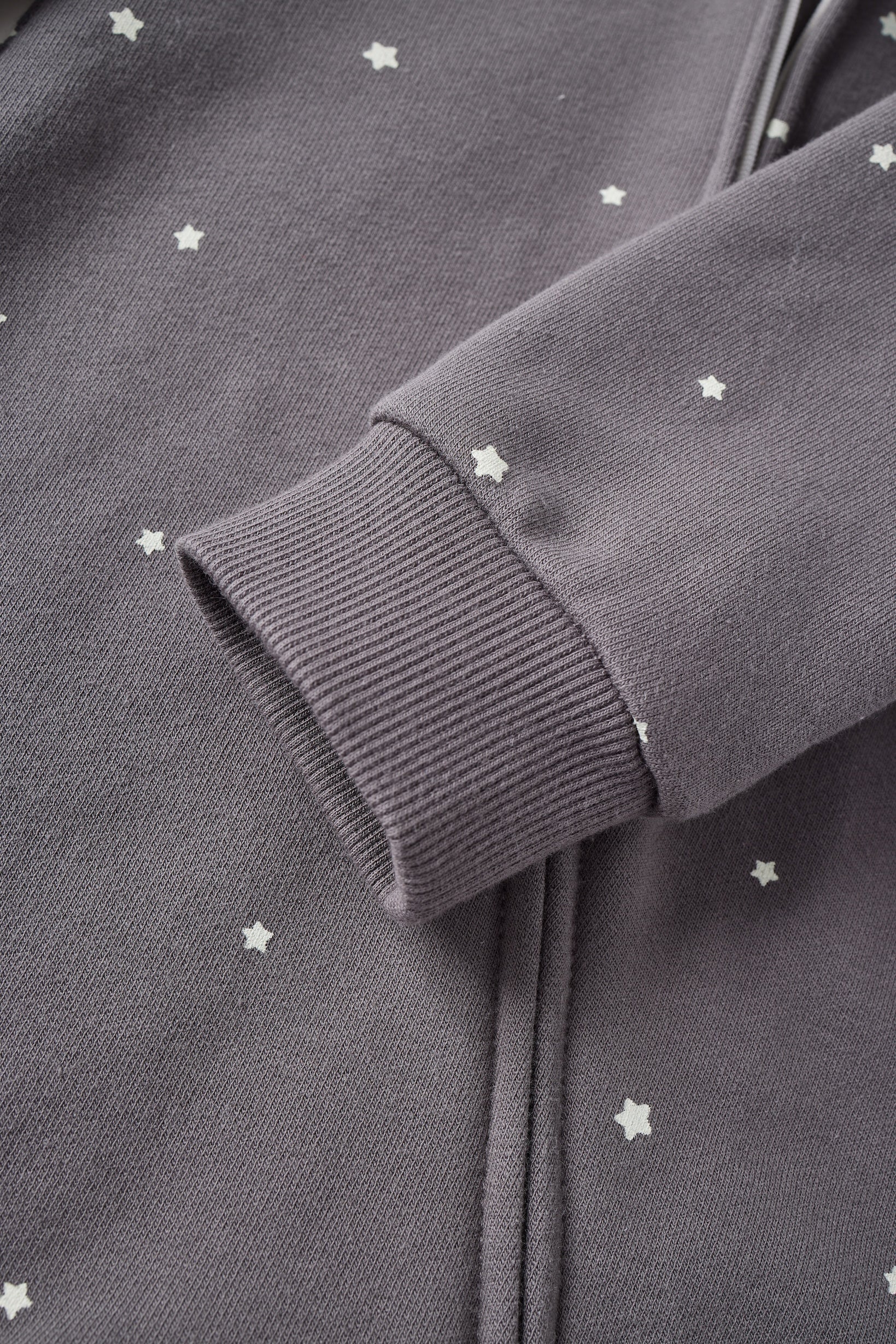 Close-up of a dark gray sweatshirt with star patterns on a plain background