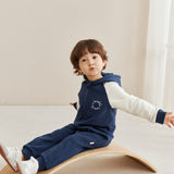 Child sitting on a wooden balance board wearing a navy blue outfit with norsu logo.