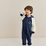 Child wearing a navy and white sleeper with a hood on a beige background