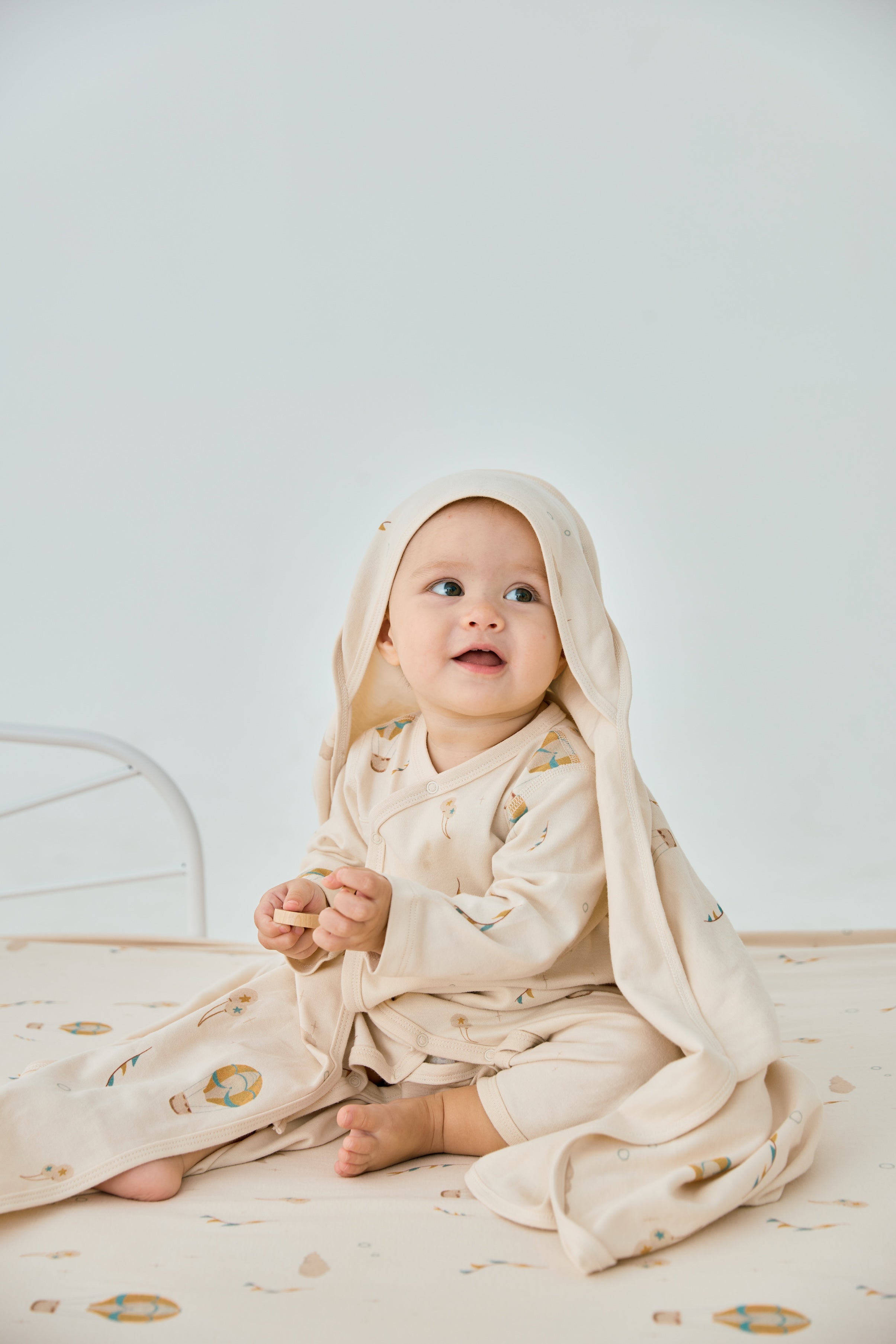 baby sitting on the bed and smilling to the camera