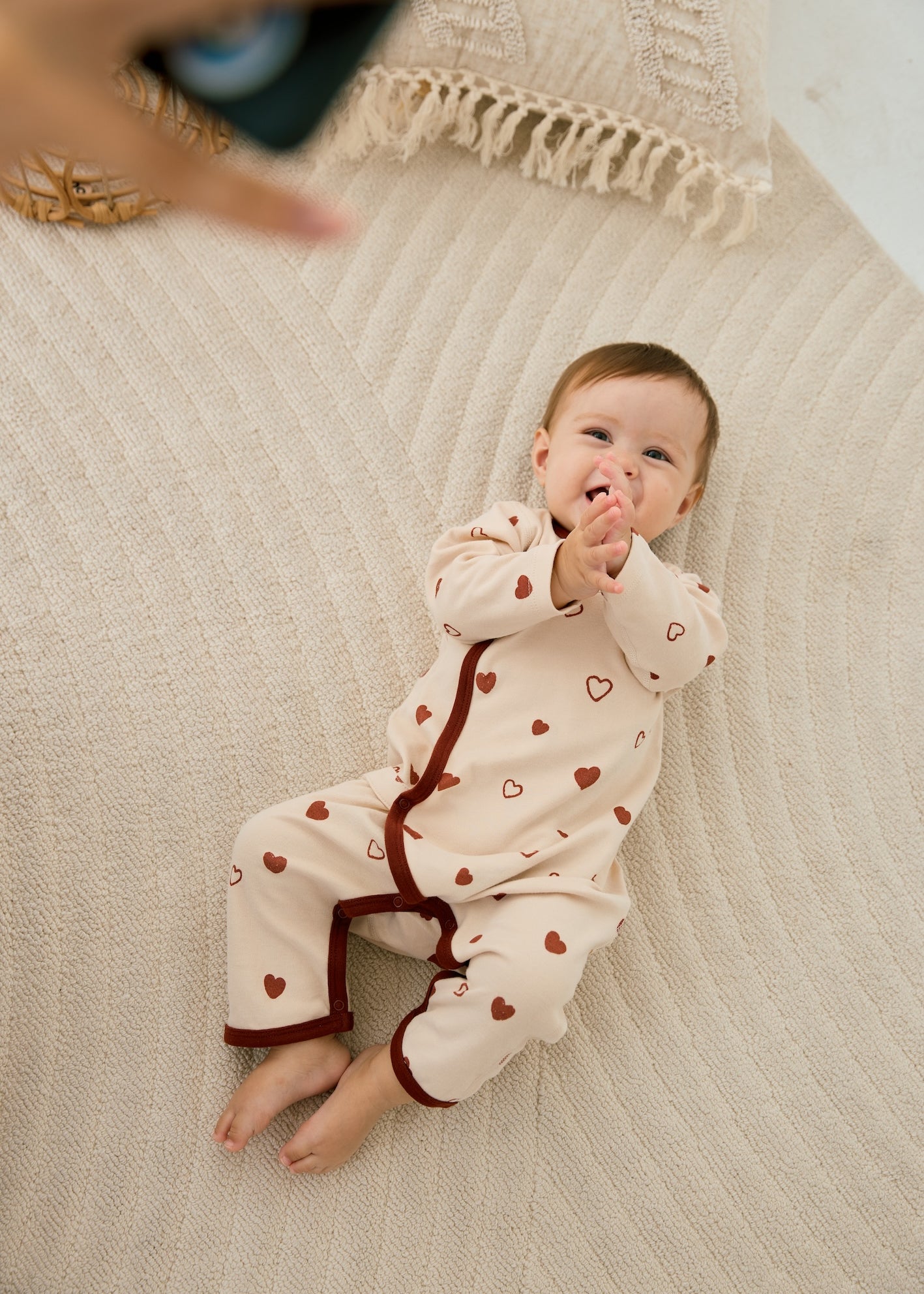 norsu organic baby kimono sleeper hearts baby lying on the ground