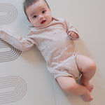 Baby lying on a white mat with a soft focus background