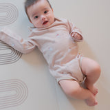 Baby lying on a white mat with a soft focus background
