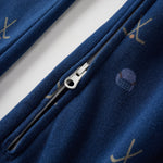 Close-up of a blue garment with a zipper and embroidered designs on a white background