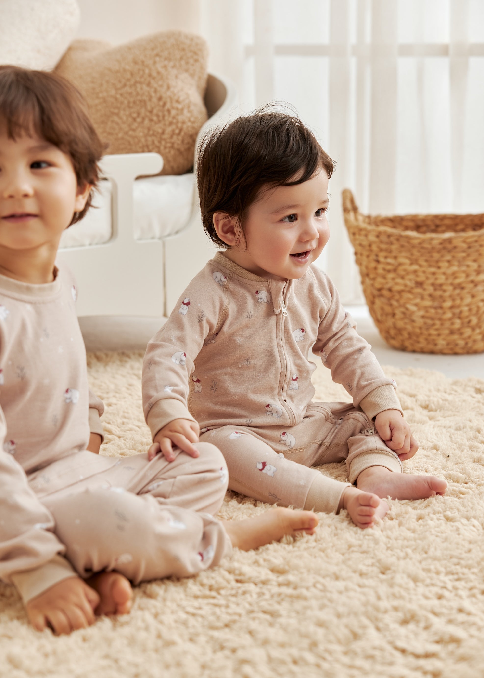 Two children sitting on a carpeted floor in a bright room with natural light.