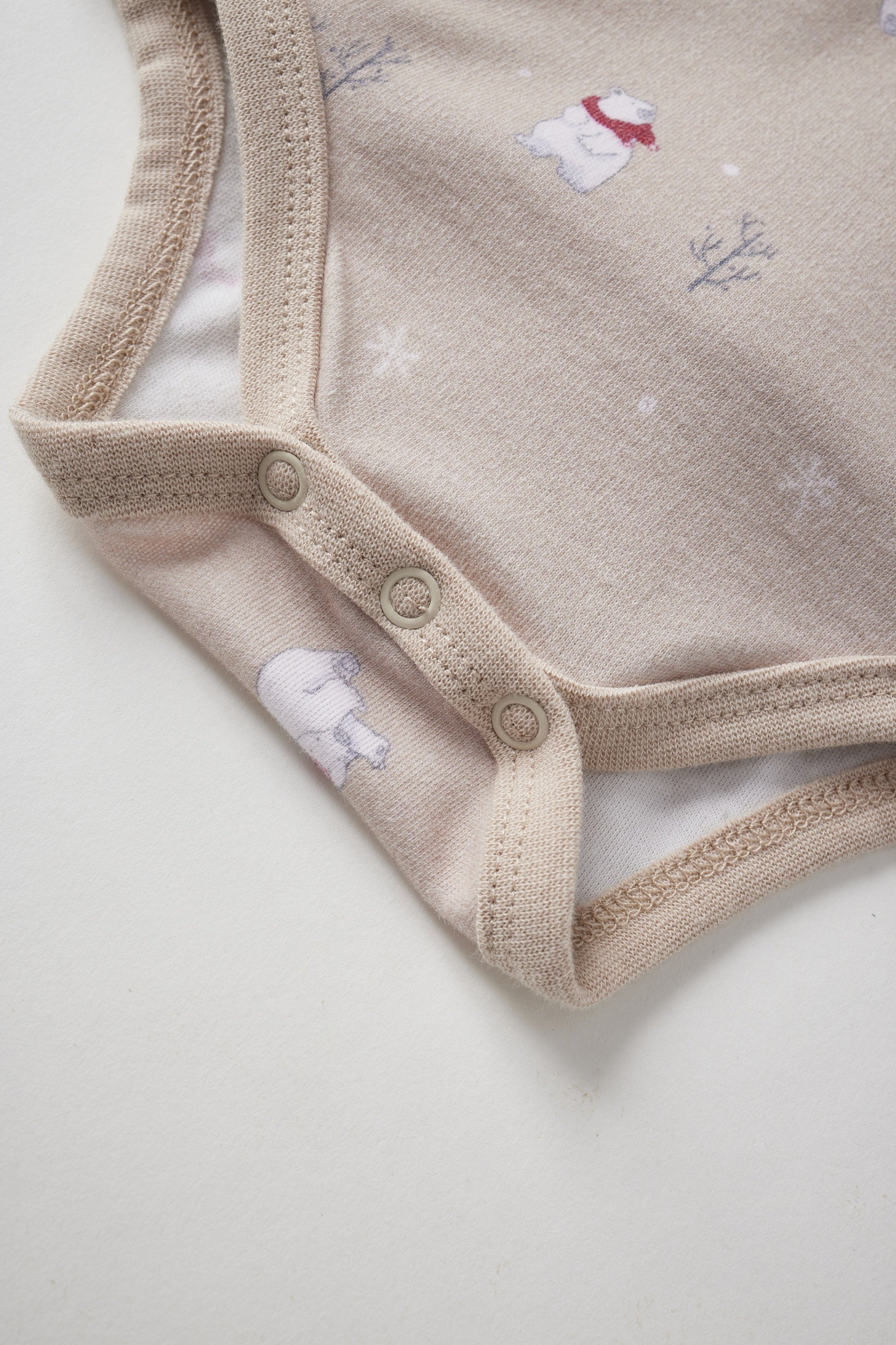 Beige baby onesie with embroidered snow polar bear on a light background