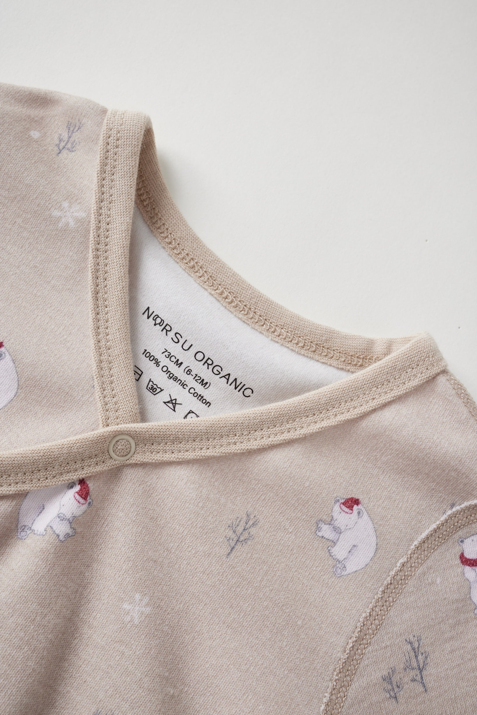 Close-up of a baby outfit with polar bear and snowflake pattern on a neutral background