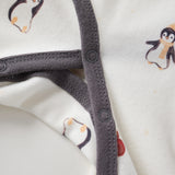 Close-up of a baby outfit with penguin and apple designs on a white background
