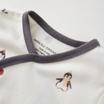 Close-up of a baby outfit with penguin design and visible brand label on a white background