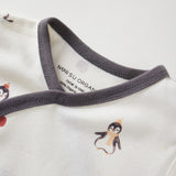 Close-up of a baby outfit with penguin design and visible brand label on a white background